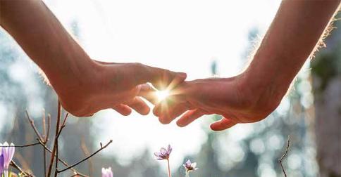 Primo piano di mani quasi congiunte che coprono la luce solare
